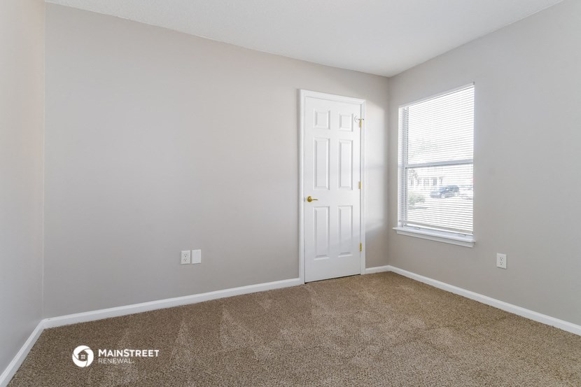 a bedroom with a door and a window and a carpeted floor
