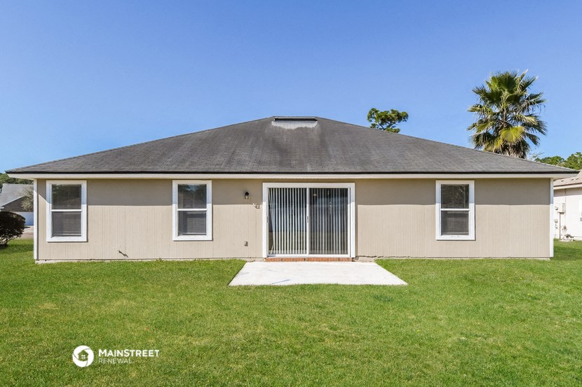a beige house with a yard and a palm tree