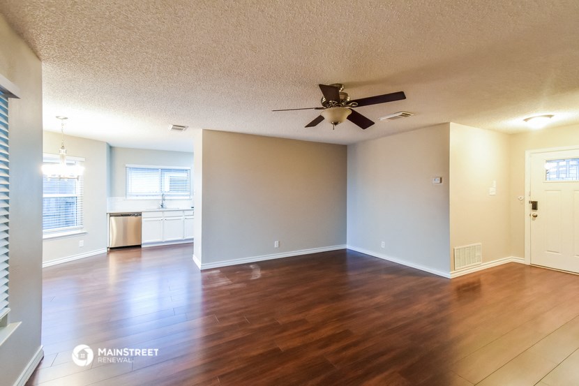 an empty living room with wood floors and a ceiling fan