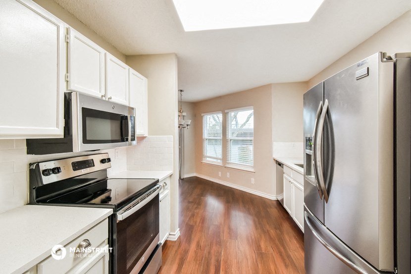 a modern kitchen with stainless steel appliances and white cabinets