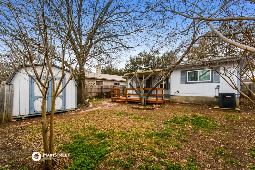 a small white house with a yard and a deck