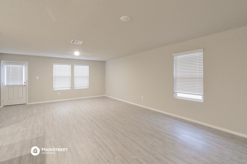 the spacious living room with wood flooring and white walls