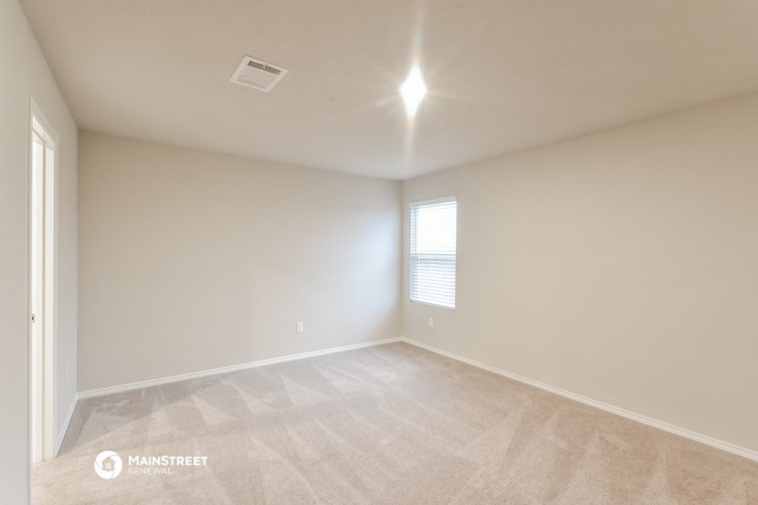 the spacious living room with white walls and a window