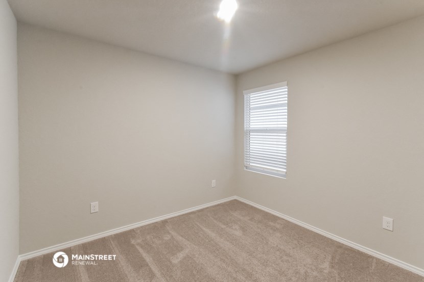 the spacious living room with carpeting and a window