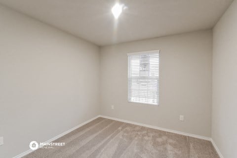 the spacious living room of a manufactured home with carpet and a window