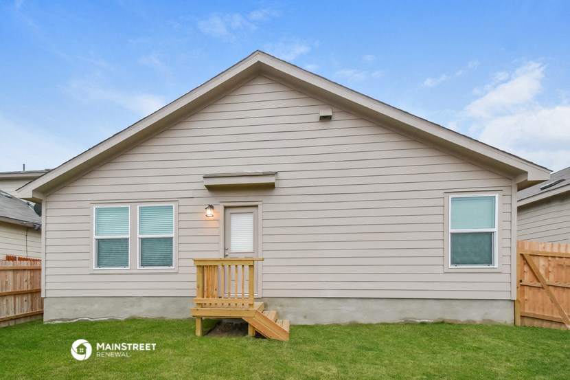 the outside of a house with a deck and a bench