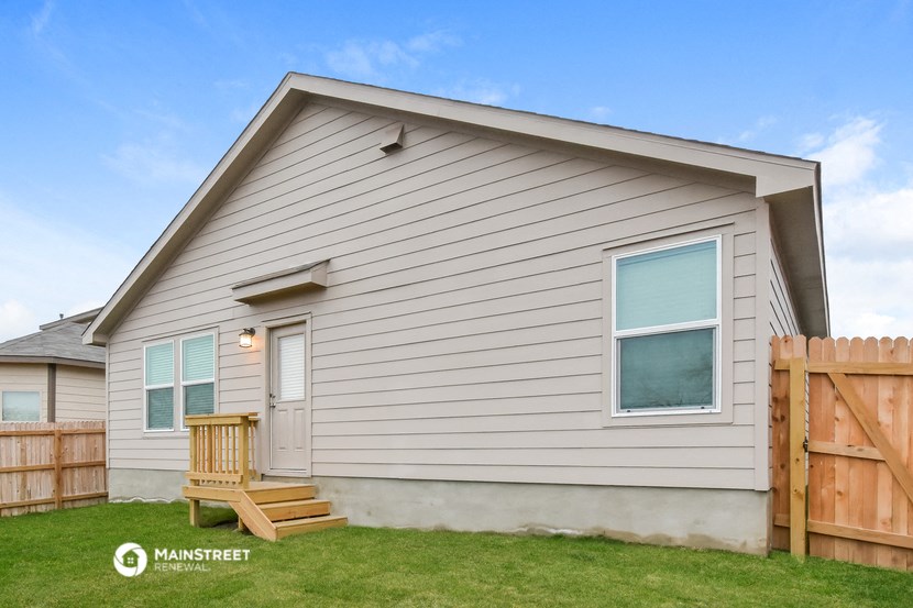 the exterior of a house with a wooden fence and a deck chair