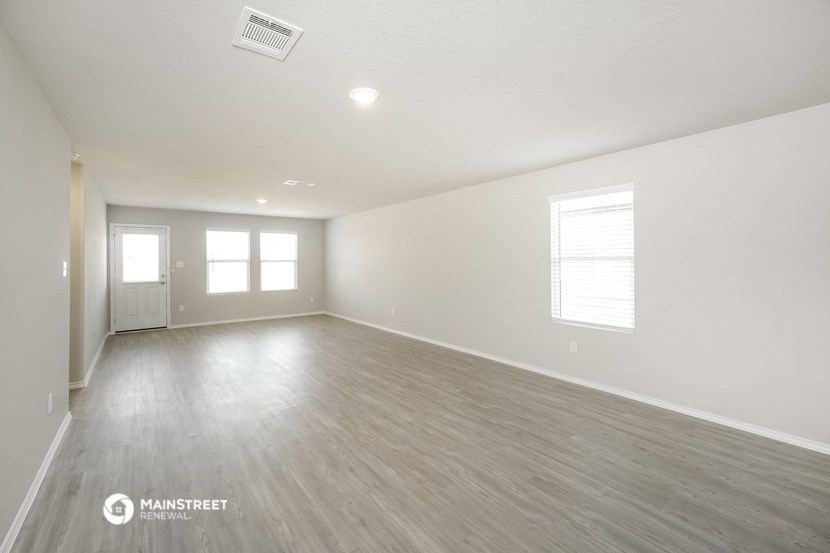the spacious living room with wood flooring and white walls