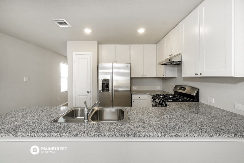 a kitchen with granite counter tops and a stainless steel refrigerator