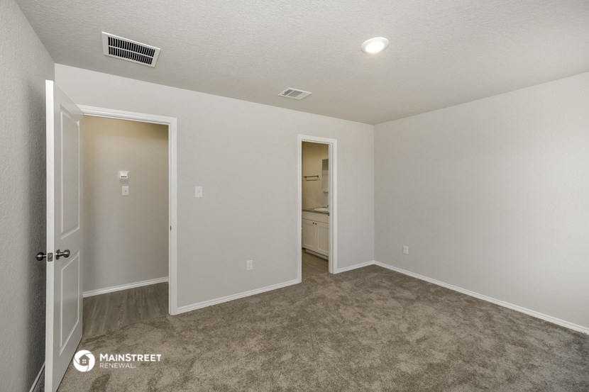 a spacious living room with carpet and a door to the bathroom