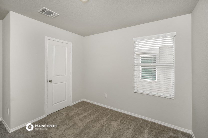 the spacious bedroom of this manufactured home has a white door and a window