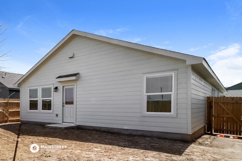 the exterior of a white house with a yard and a wooden fence