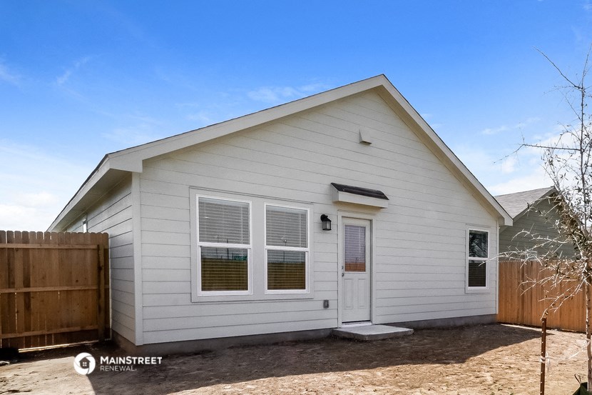 the exterior of a white home with a wooden fence and a white house