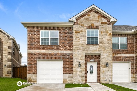 a brick house with two garage doors in front of it