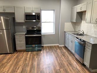 an empty kitchen with wood floors and stainless steel appliances