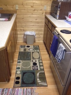 A kitchen with a rug on the floor.