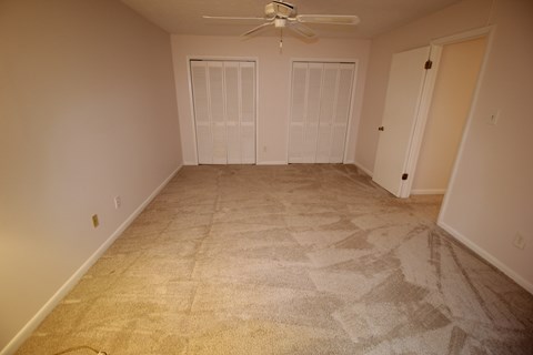a living room with carpet and a ceiling fan