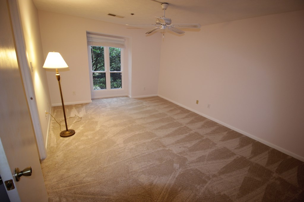 a empty living room with a ceiling fan and a window