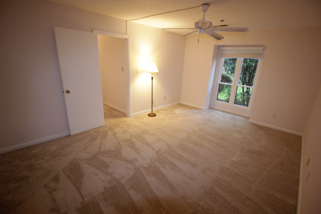 an empty living room with a ceiling fan and a window