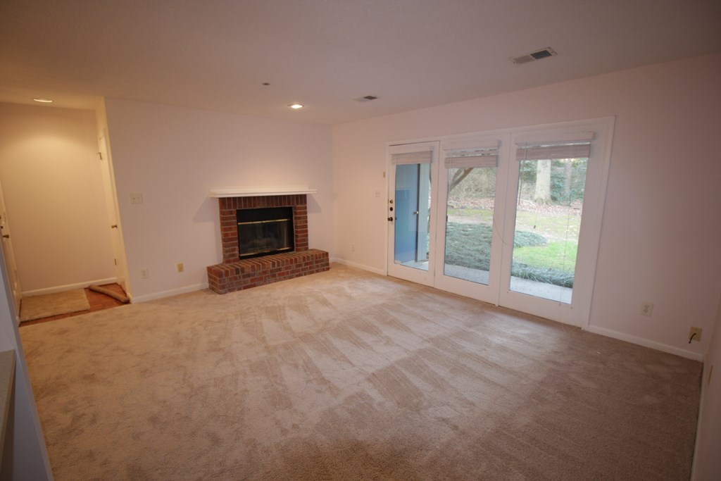 an empty living room with a fireplace and a sliding glass door