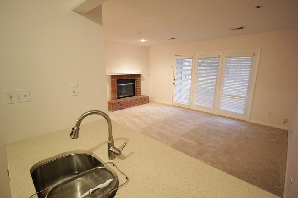 a kitchen with a sink and a living room with a fireplace