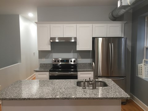 a kitchen with a granite counter top and a stainless steel refrigerator