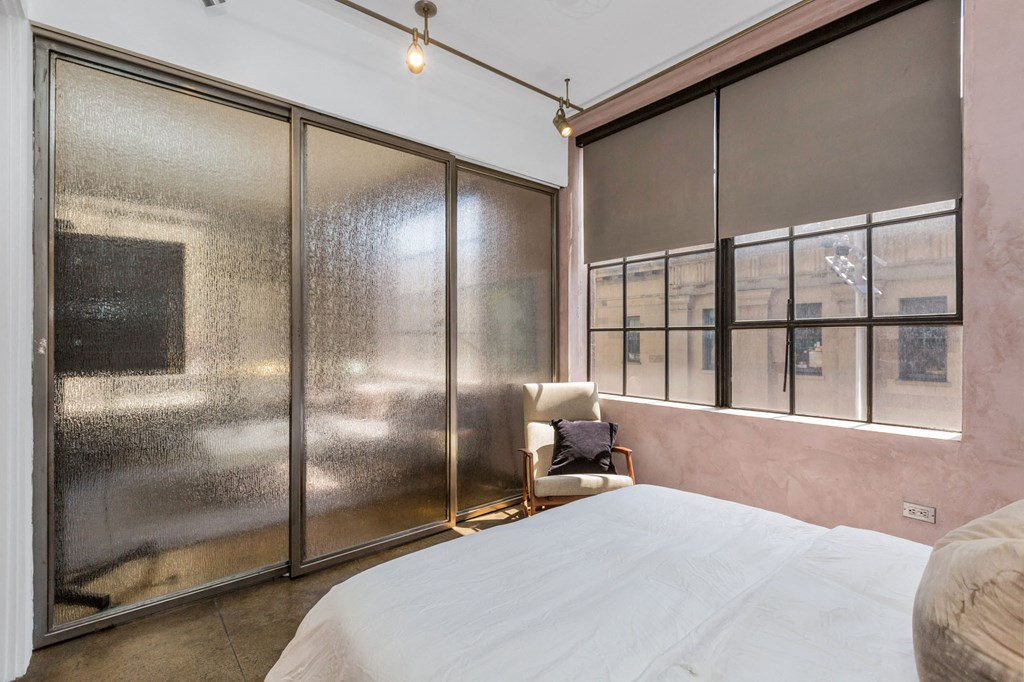 a bedroom with a bed and a large window with frosted glass