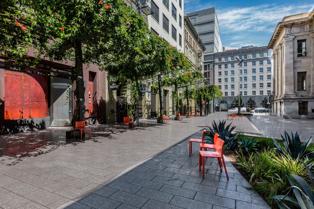a city street with red chairs and trees and buildings