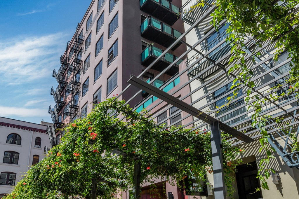 a city street with a tall building and some plants and trees