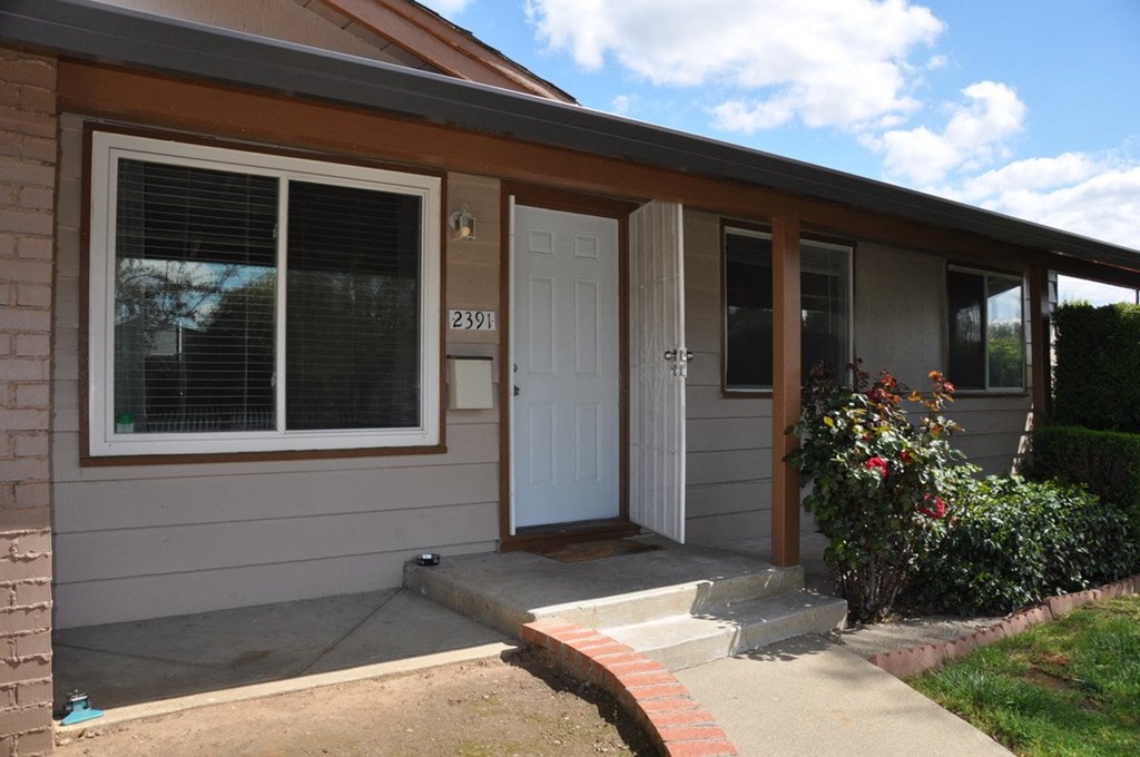 the front of a house with a porch and a white door