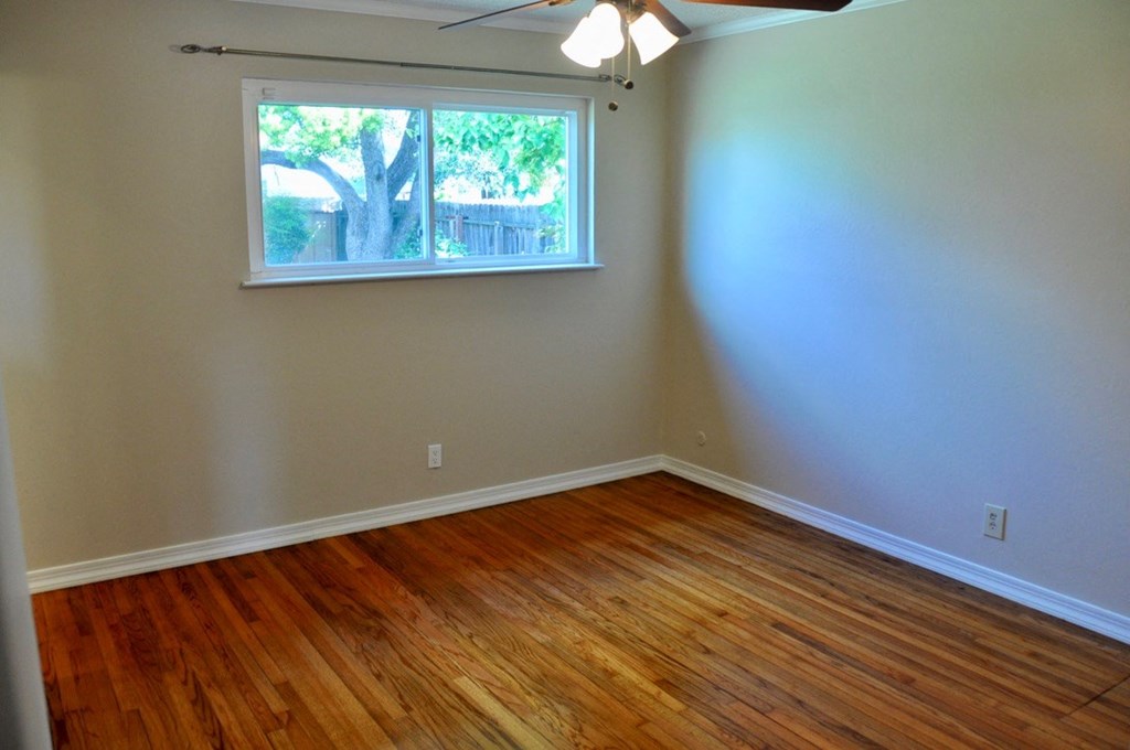 an empty room with a window and wooden floors