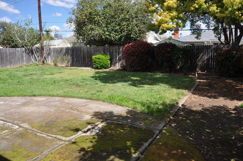 a backyard with a sidewalk and a fence