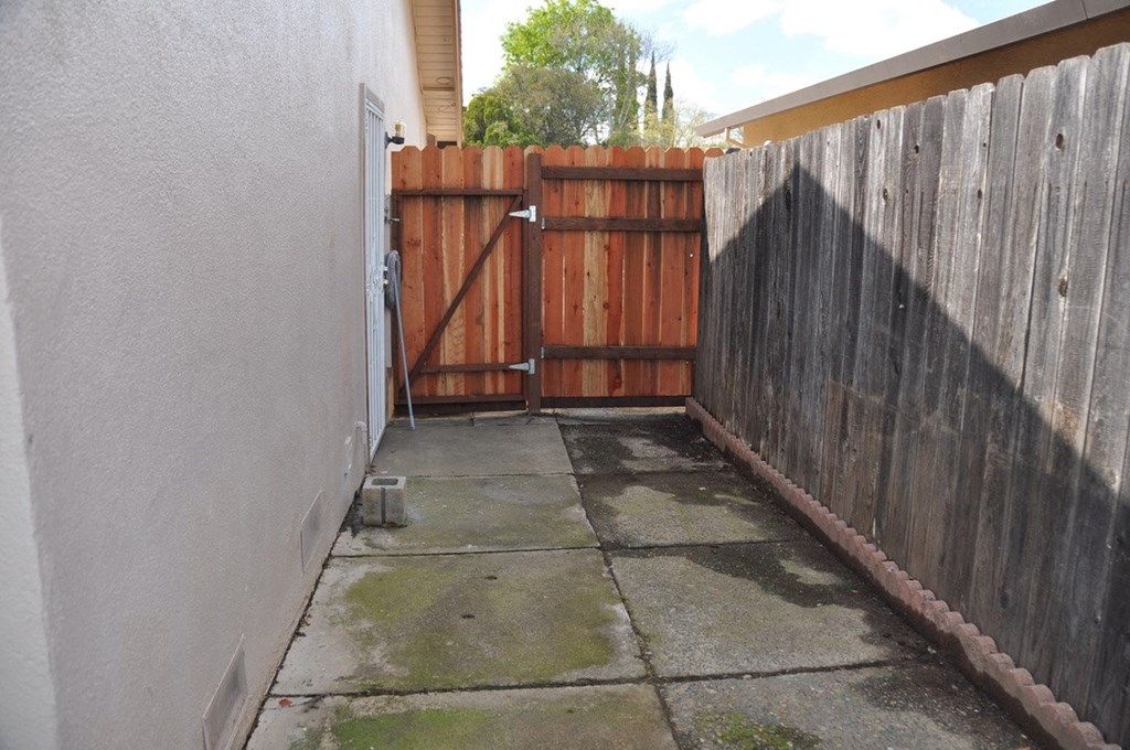 a yard with a wooden fence and a driveway with a gate