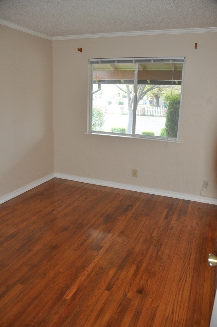 an empty room with a window and wooden floors