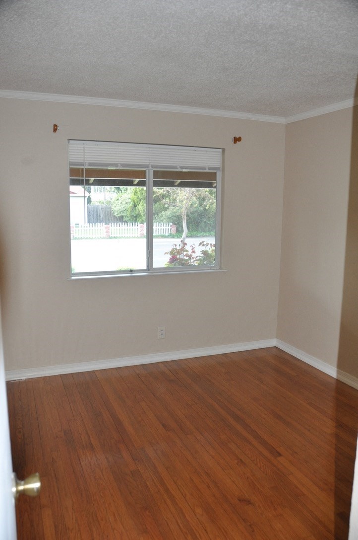 an empty living room with a window and wooden floors