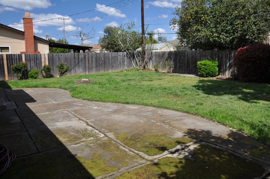a backyard with a concrete patio and a fence