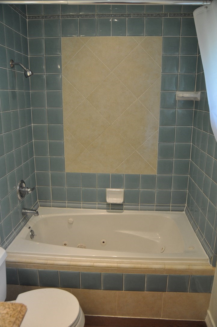 a blue tiled bathroom with a tub and a toilet