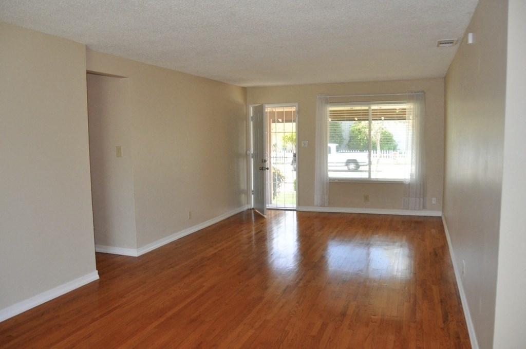 an empty living room with wooden floors and a window