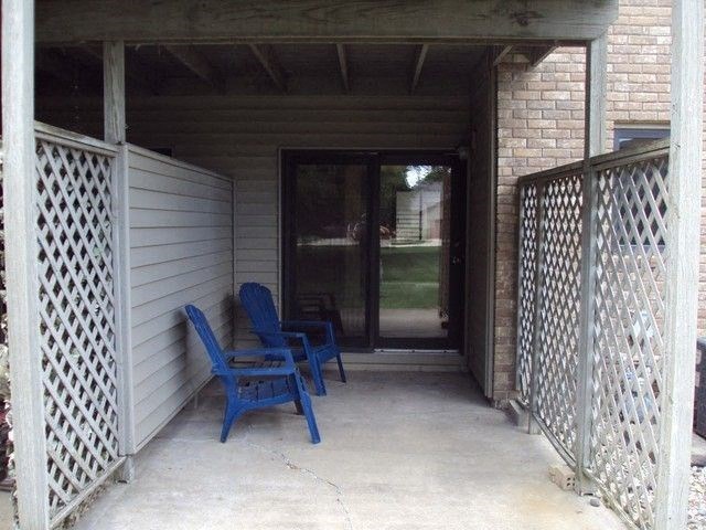 a porch with two blue chairs and a door