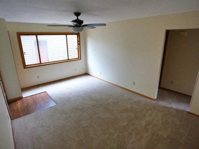 an empty living room with a ceiling fan