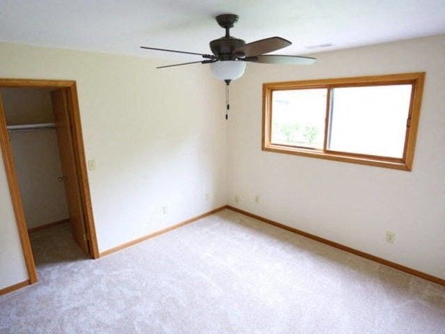 an empty living room with a ceiling fan and a closet