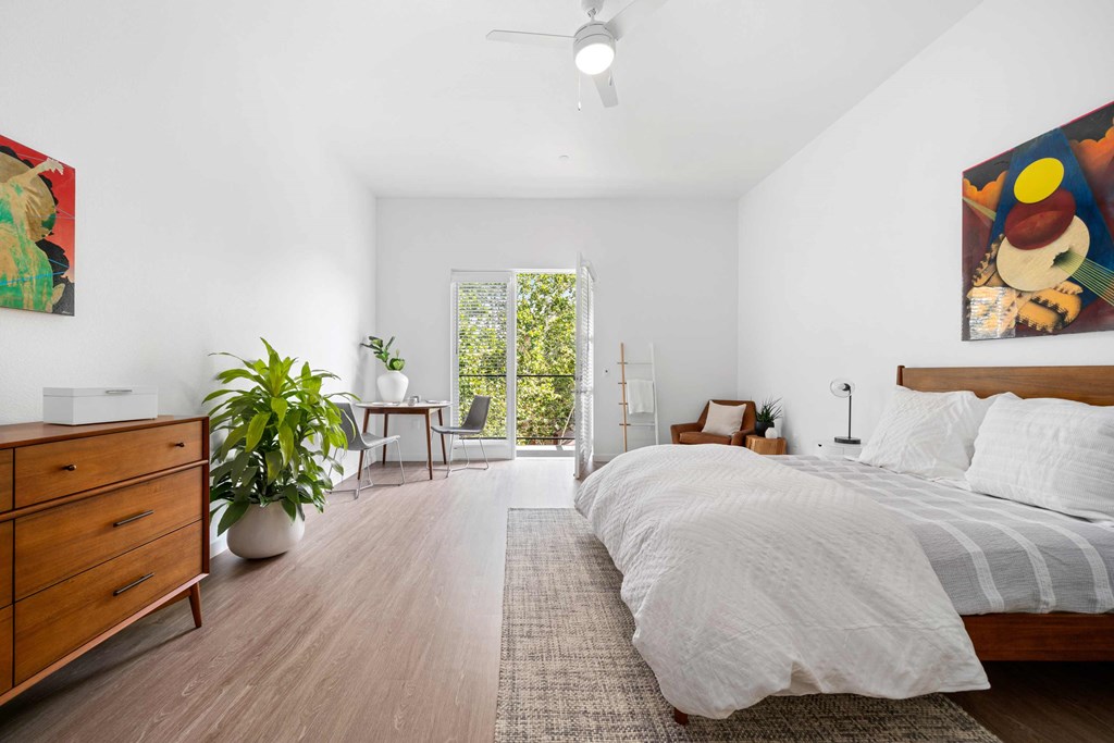 the master bedroom has a large bed and a sliding glass door to the balcony