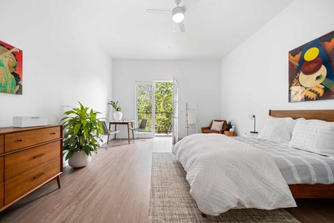the master bedroom has a large bed and a sliding glass door to the balcony