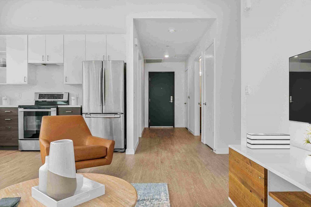 a living room with a leather chair and a kitchen with a refrigerator