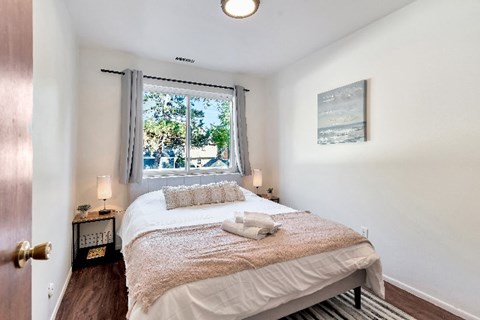 A bedroom with a bed, nightstand, and window.