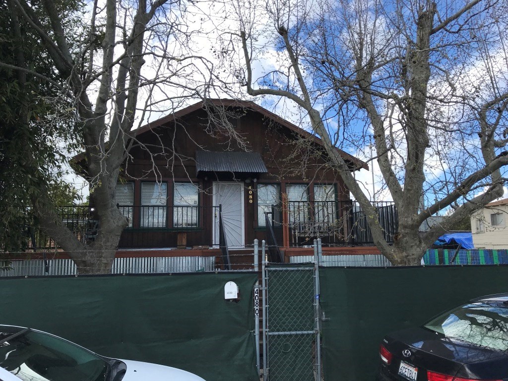 a house with a fence and cars in front of it