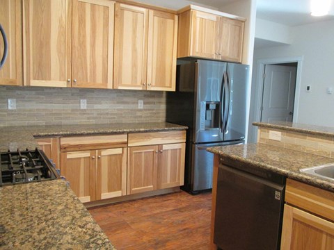 A kitchen with wooden cabinets and a black refrigerator.