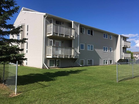 the back of an apartment building with balconies and a lawn