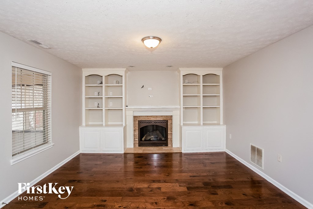 A living room with a fireplace and wooden floors.
