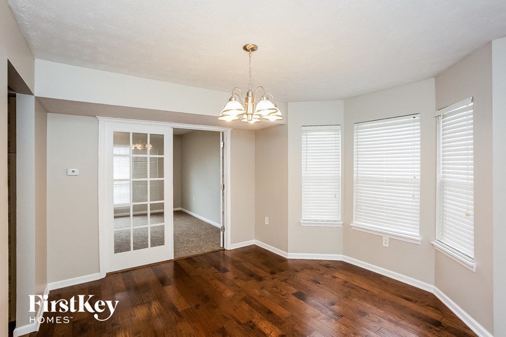 A room with wooden floors and a chandelier hanging from the ceiling.